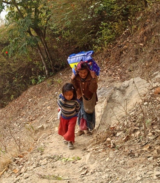 A grandmother and her granddaughter walk home from a distant market 